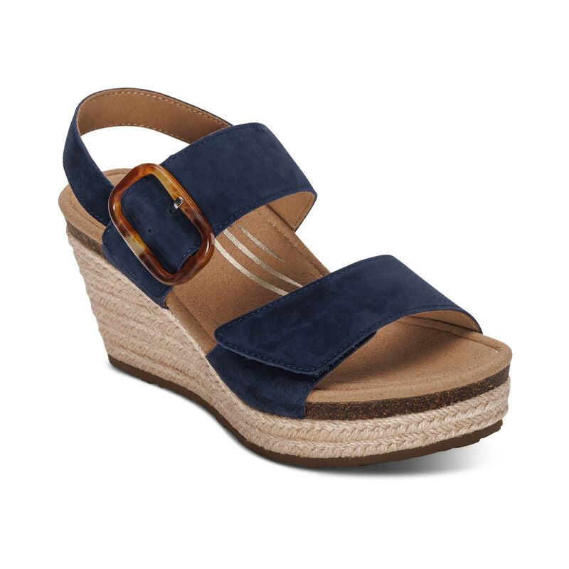 The Aetrex Women's Ashley Espadrille Wedge Navy by AETREX WORLDWide INC features navy suede straps, a brown buckle, and a jute-wrapped platform. Enjoy cushioned comfort and arch support in these stylish leather wedges.