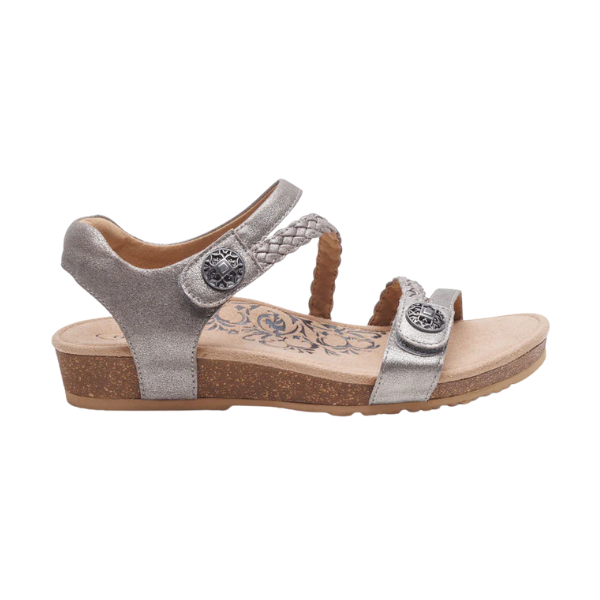 The Aetrex Women's Jillian Brushed-Silver by AETREX WORLDWide INC is a metallic silver orthotic sandal with a low cork wedge, braided and smooth straps, metal buttons, floral insole pattern, and memory foam cushioning—shown side view.