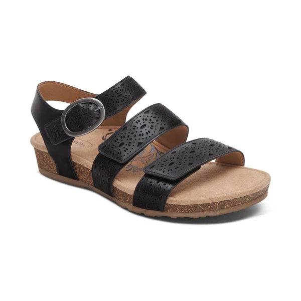 The Aetrex Women's Lilly Cutout Black sandal by AETREX WORLDWide INC features three adjustable perforated leather straps, a cork wedge sole, round silver buckle, tan cushioned insole with arch support, and floral design for all-day comfort.