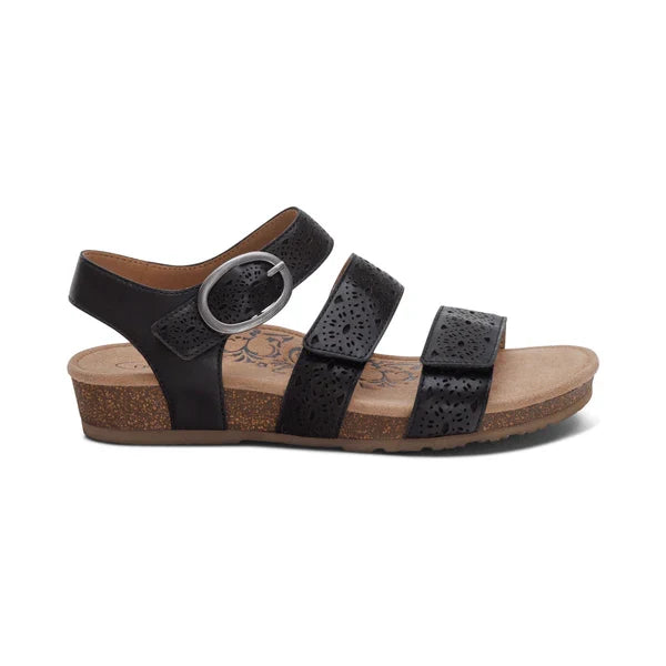 The Aetrex Women's Lilly Cutout Black sandals by AETREX WORLDWide INC feature three adjustable black straps with a silver buckle, a cushioned memory foam footbed for arch support, a cork wedge sole, and subtle perforated detailing.