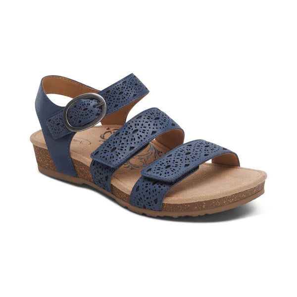 The Aetrex Women's Lilly Cutout Navy by AETREX WORLDWide INC has three perforated straps, a round ankle buckle, open toe, low cork wedge heel, and a cushioned memory foam footbed for all-day comfort.