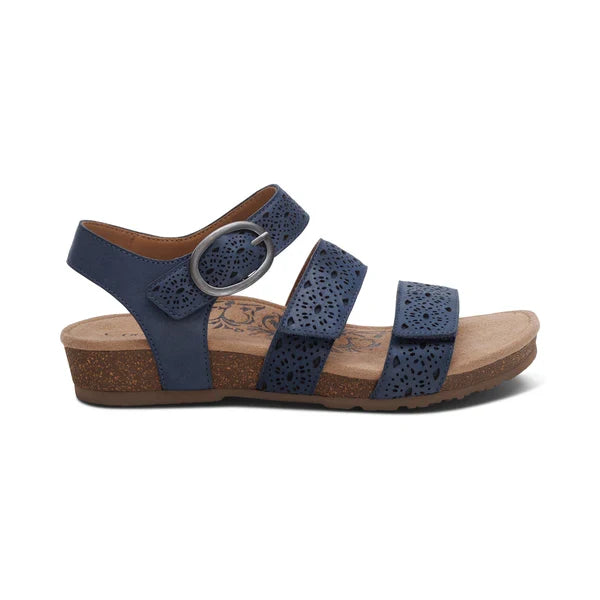 The Aetrex Women's Lilly Cutout Navy sandals by AETREX WORLDWide INC offer three adjustable straps, decorative cut-outs, a large silver buckle, and a cork-like low wedge heel. Enjoy all-day comfort with a cushioned memory foam footbed.