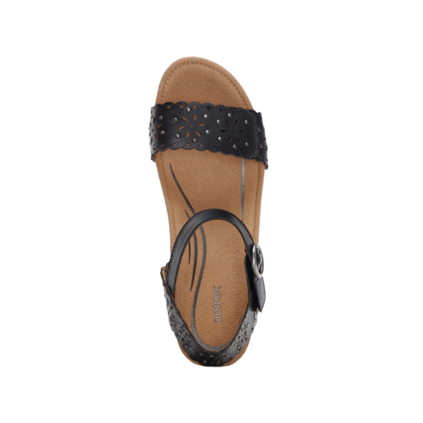 The Aetrex Women's Sydney Black Cutout sandals by AETREX WORLDWide INC feature a black perforated strap, ankle buckle, and tan cushioned footbed with decorative stitching—ideal arch support for all-day comfort.