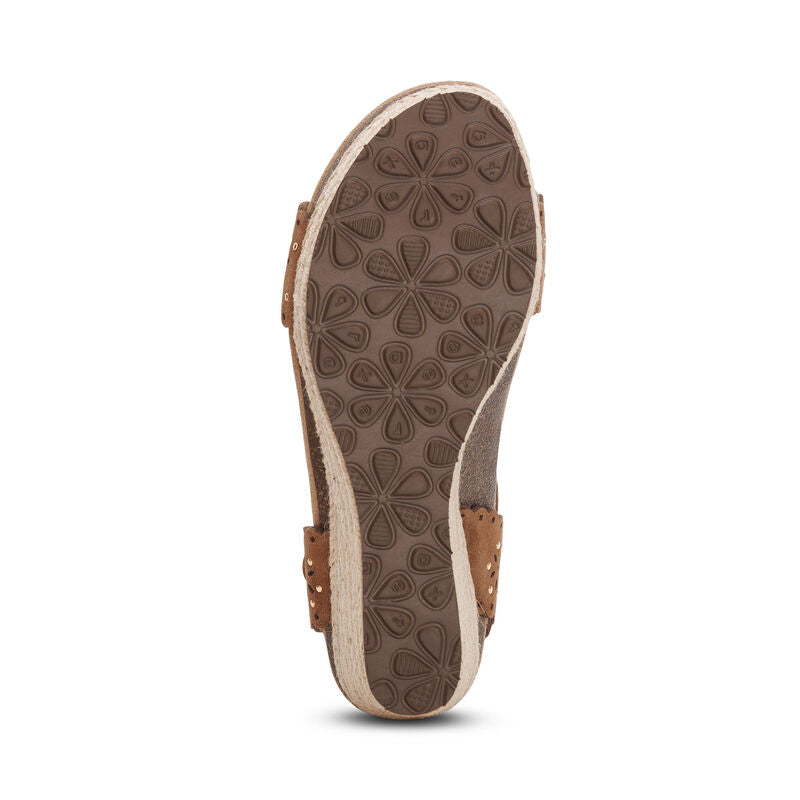 The image shows the bottom of an Aetrex Women's Sydney Scotch Cutout sandal by AETREX WORLDWide INC, featuring a textured sole with floral patterns for grip, tan cutout straps, arch support, and a slightly raised heel for comfort.