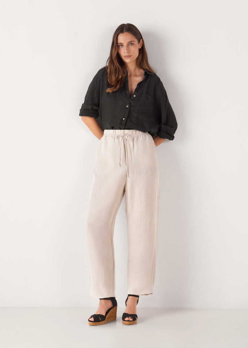 Full-length model wearing black canvas ankle-strap wedge espadrilles with a natural jute platform