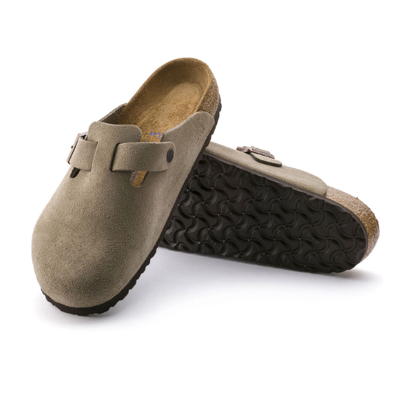 A pair of BIRKENSTOCK Mens Boston Soft Footbed Taupe clogs in suede, featuring black textured rubber soles and adjustable side buckles, one shoe upright and the other tilted to display the sole.
