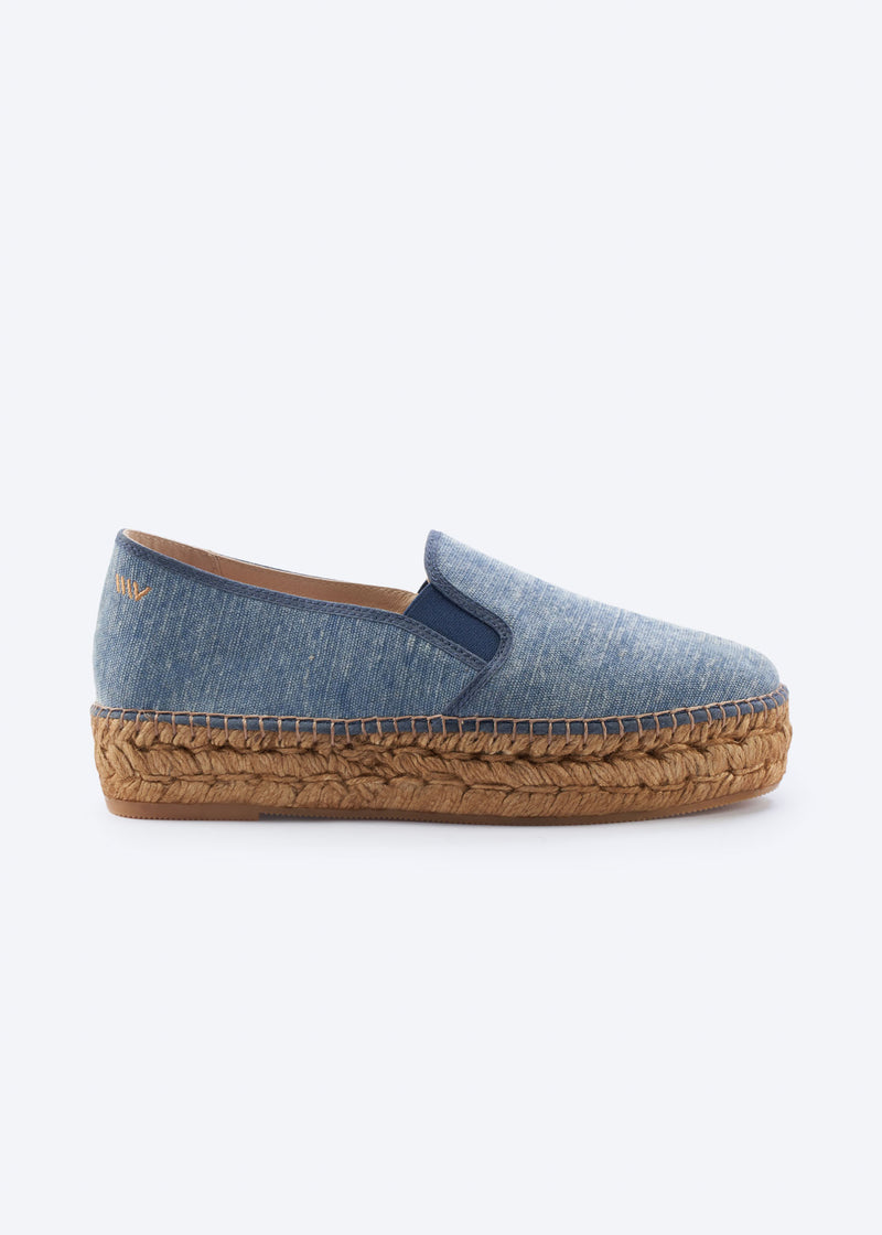 Side view of washed denim espadrille flat with side gore detail and a natural braided jute platform sole, handcrafted in Spain