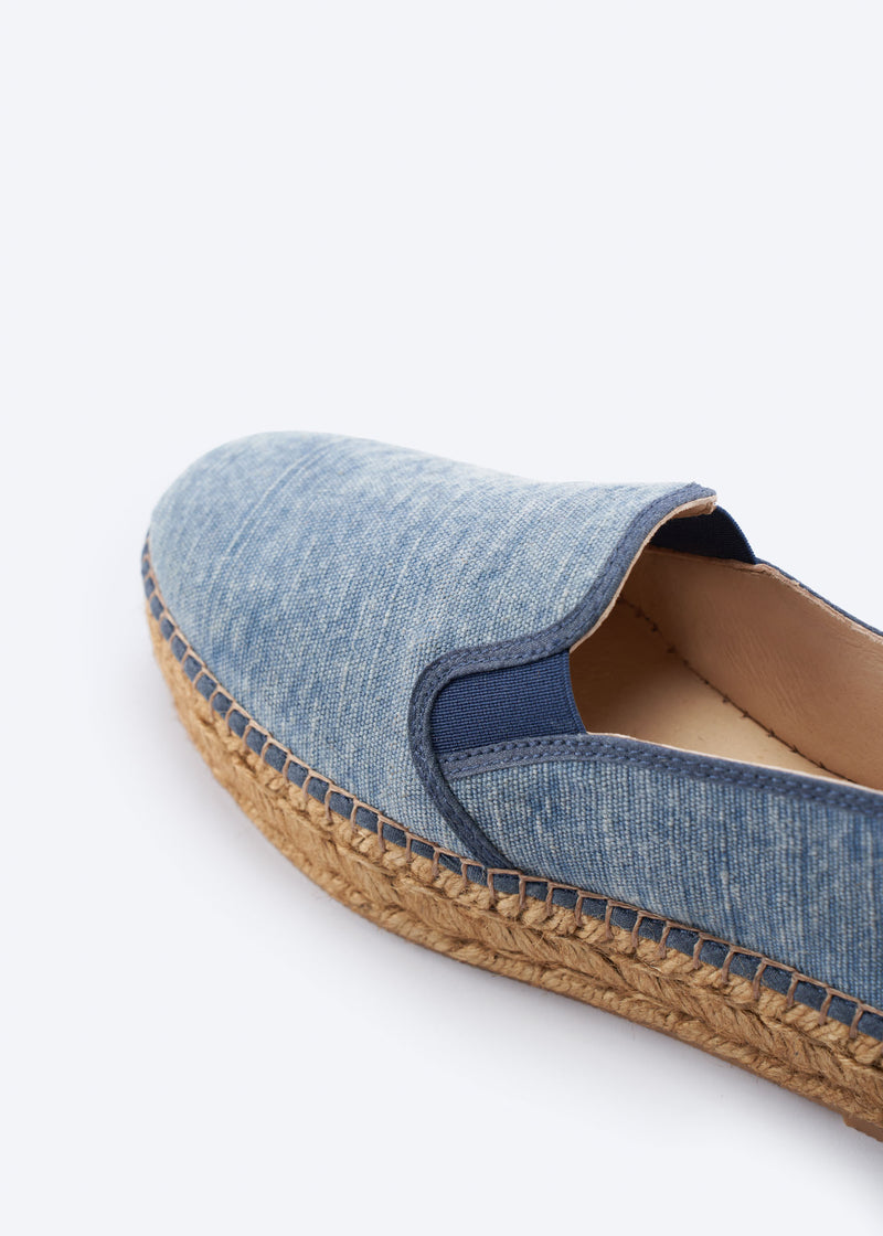 Close-up of washed denim espadrille flat with side gore detail and a natural braided jute platform sole, handcrafted in Spain