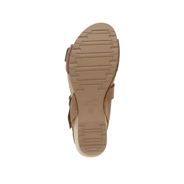 Bottom view of Dansko Womens Trinity Tan Burnished Nubuck sandal, featuring a ribbed rubber sole with slight wedge heel and embossed DANSKO logo near the arch for added support and comfort.