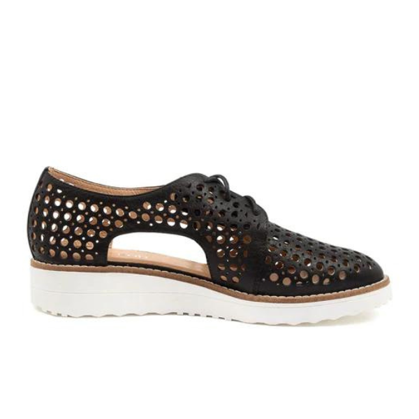 The Django & Juliette Womens Onstage Black Leather shoe by DJANGO & JULIETT features a lace-up design with circular cut-outs, low heel, and thick white sole—combining chic athleisure style with comfort for subtle flair and foot pain relief.
