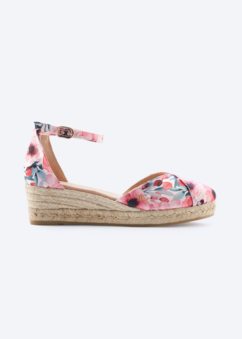 Side view of floral print wedge espadrille with ankle strap, closed toe, and a natural braided jute wedge, handcrafted in Spain