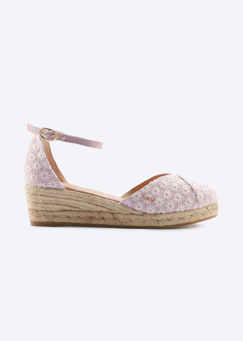 Side view of pale pink floral wedge espadrille with an ankle strap, closed toe, and natural braided jute wedge, handcrafted in Spain