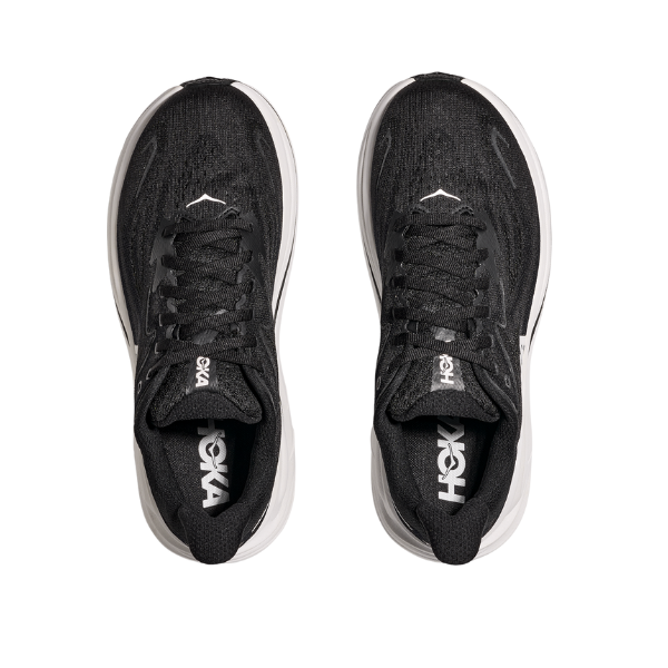 A pair of HOKA Womens Clifton 10 Wide Black/White running shoes with white midsoles, seen from above on a white background. The HOKA logo appears on the tongue, highlighting this popular cushioned style.
