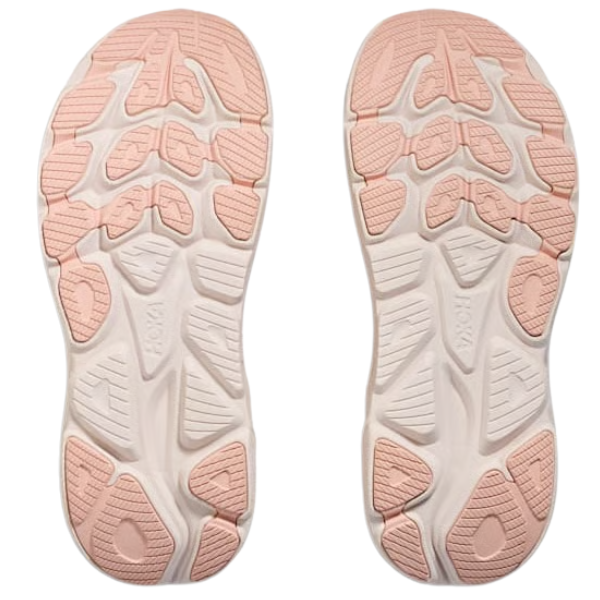 The HOKA Women's Clifton 10 Wide Blush features light pink and white soles with textured tread patterns and HOKA embossed on each, ideal for fans of cushioned trainers.