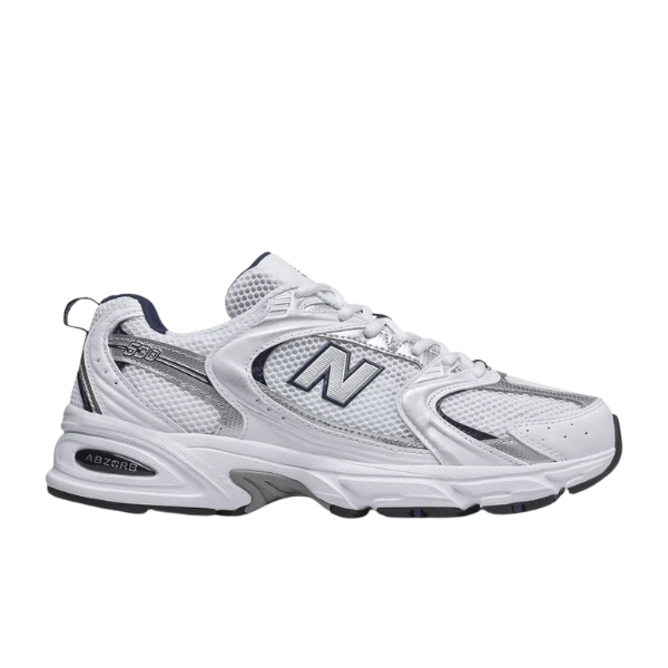 The New Balance Unisex 530 White/Grey sneaker features mesh panels, a bold N logo, and dark blue accents. Shown on a plain white background, this NEW BALANCE shoe combines white and gray tones for an athletic look.