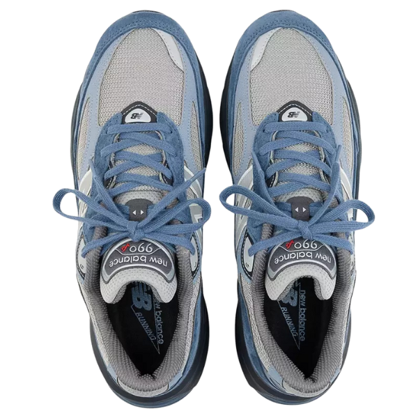 A pair of NEW BALANCE Unisex 990v6 Blue/Grey sneakers with blue laces, gray and blue shades, and visible logos on the tongues and insoles—showcasing a classic running shoe style.