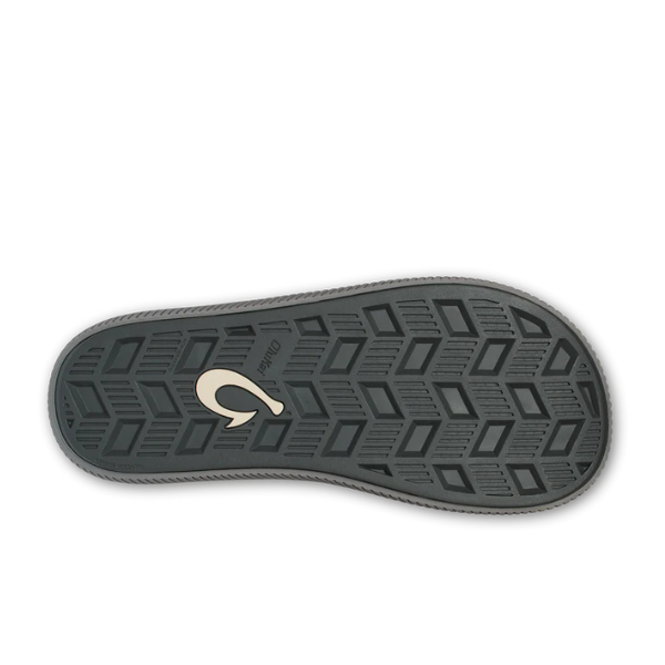 The image displays the sole of the Olukai Mens Ulele Dark Blue shoe by OLUKAI, featuring a black and gray geometric tread and a beige logo near the heel—crafted for comfort and foot pain relief.
