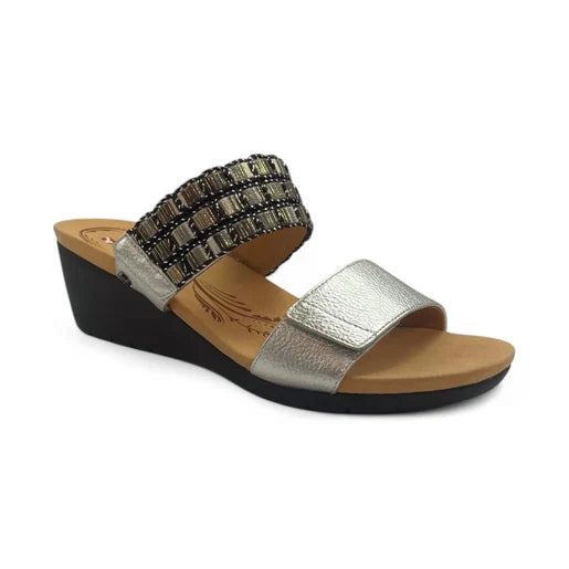 The Revere Womens Sorrento Silver by REVERE is an orthotic wedge sandal with a black sole, tan footbed, metallic silver front strap, and a decorative beaded woven upper—perfect for style and support.