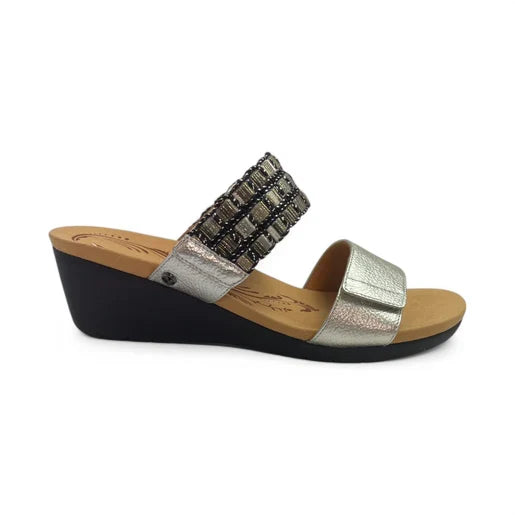 The REVERE Revere Womens Sorrento Silver is an orthotic wedge sandal with a black sole, cushioned tan footbed, metallic silver front strap, and beaded upper strap—stylish and comfortable for all-day support.