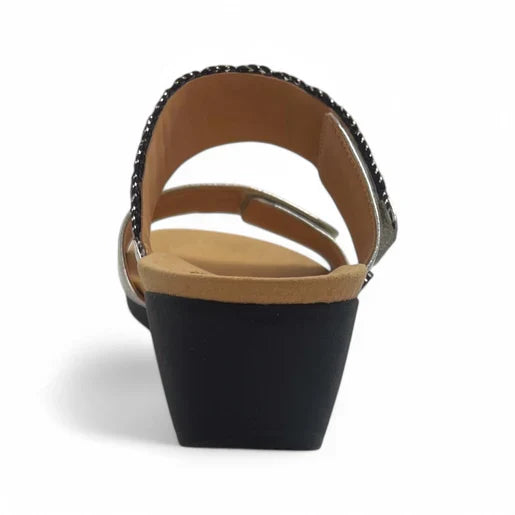 A rear view of the Revere Womens Sorrento Silver open-toe wedge sandal by REVERE, featuring a tan footbed, black low wedge heel, and decorative strap—ideal support for plantar fasciitis; photographed on a white background.