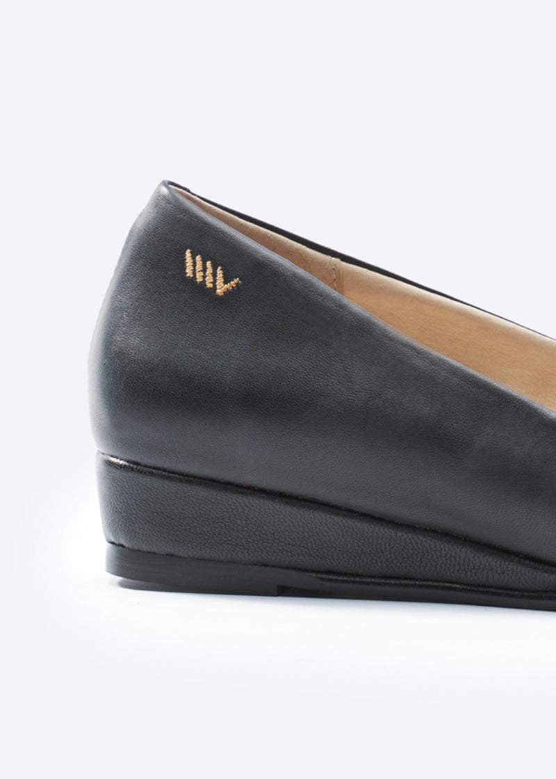 Black flat shoe with a visible brand logo on a light gray background