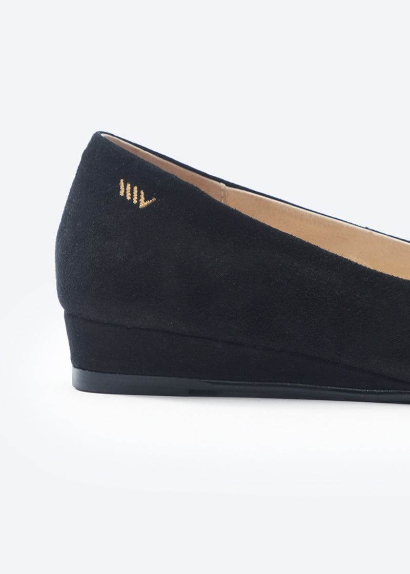 Black suede flat shoe on a white background