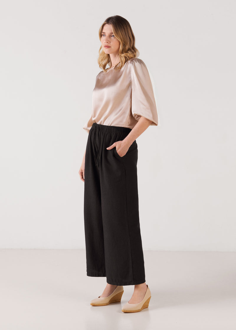 Full-length model wearing beige canvas slip-on wedge espadrilles with a natural jute sole