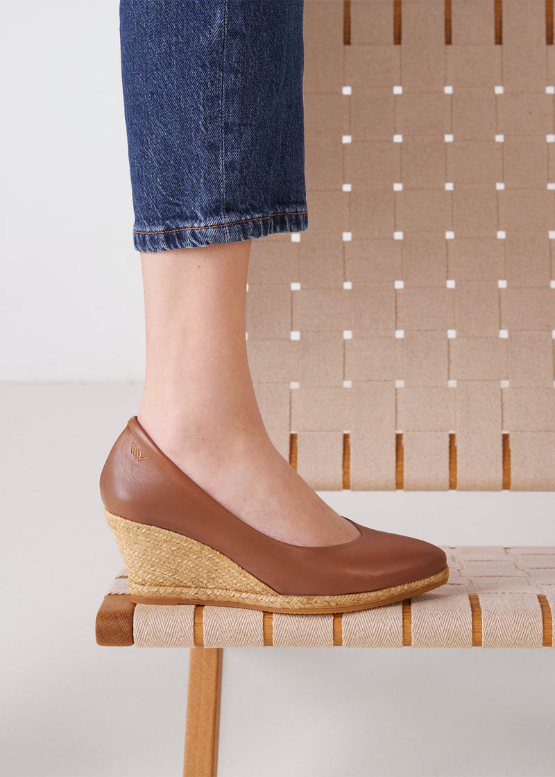 Close-up of a brown leather espadrille wedge pump worn on foot.