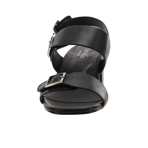 Front view of Sovella Womens Celeste Sandal in black leather, featuring two adjustable buckle straps (toe and ankle), a low heel, cushioned footbed, open-toe design, and SOVELLA-branded insole.