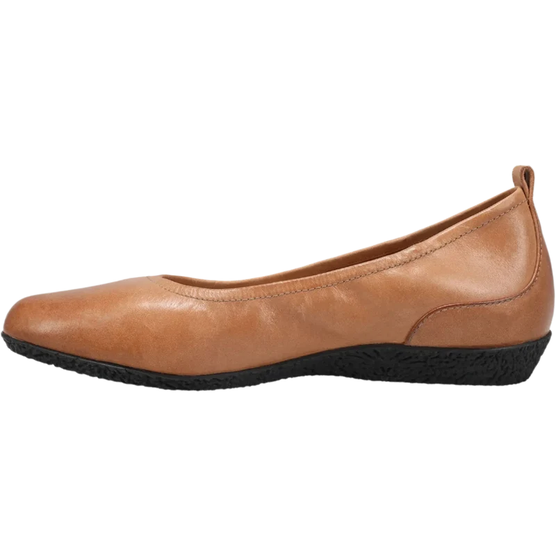 The TAOS Taos Womens Chit Chat Caramel is a tan leather flat with a rounded toe, black textured sole, small heel pull tab, and arch support for comfort—shown in side view. Ideal for everyday wear.