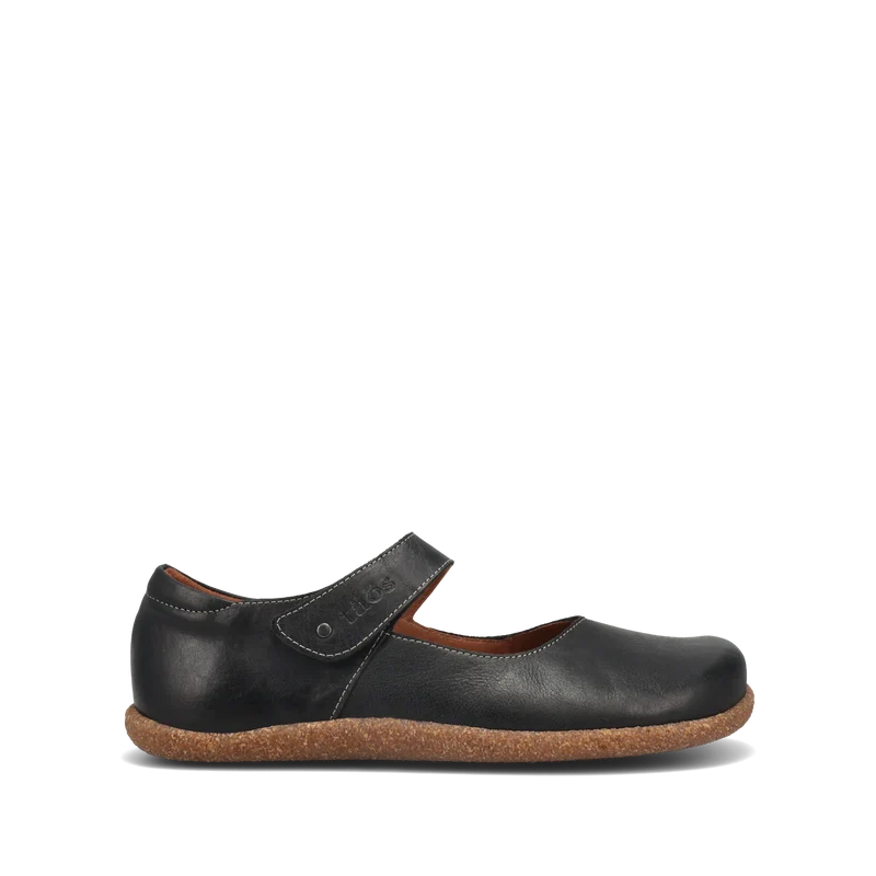 The TAOS Women's Ultimate Leather Mary Jane in black features arch support, a Velcro strap, and a textured brown sole, shown singly against a plain white background.