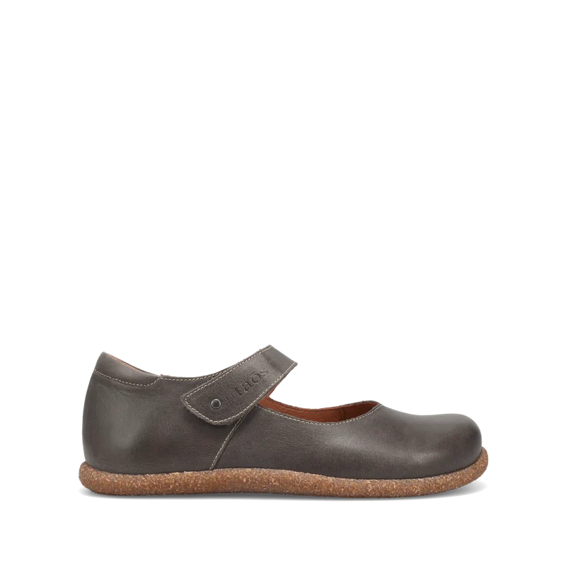 The Taos Women's Ultimate Leather Mary Jane in grey by TAOS features a hook-and-loop strap, textured cork sole, and built-in arch support, shown as a single shoe against a plain white background.