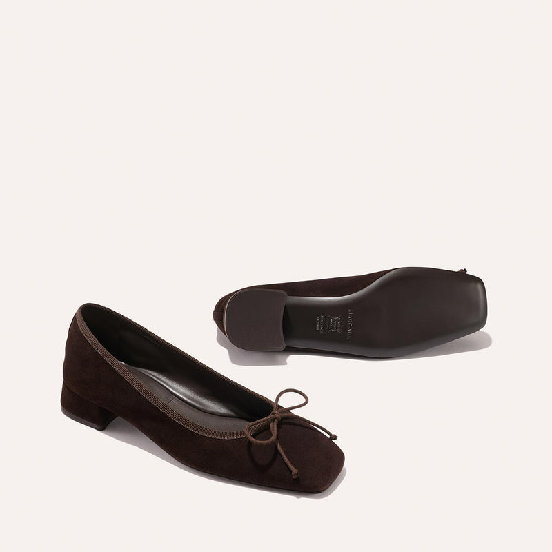 The Ada - Espresso Suede by margaux-development: low-heeled dark brown suede ballet pumps with bow details and sacchetto construction for a glove-like fit. Shown upright and on its side to display the sole, set against a light background.