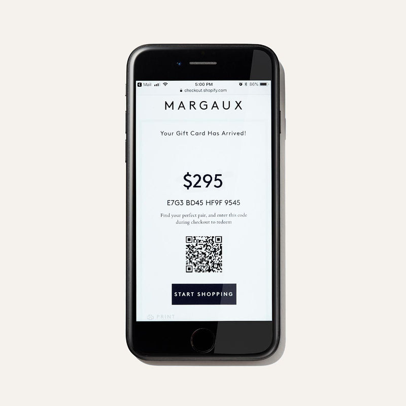 A smartphone displays The Bridal Atelier E-Gift Card by Margaux, valued at $295, with a redeemable code, QR code, and Start Shopping button on a white background—an ideal gift for luxurious bridal shoes.
