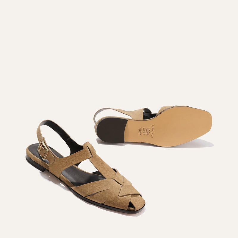 Tan sandals with a black sole on a white background
