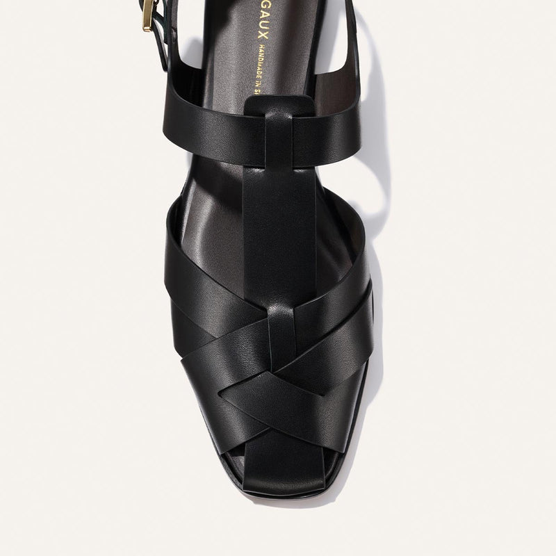 Black sandal with woven design on a white background