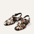 Pair of sandals with a cow print pattern on a light beige background
