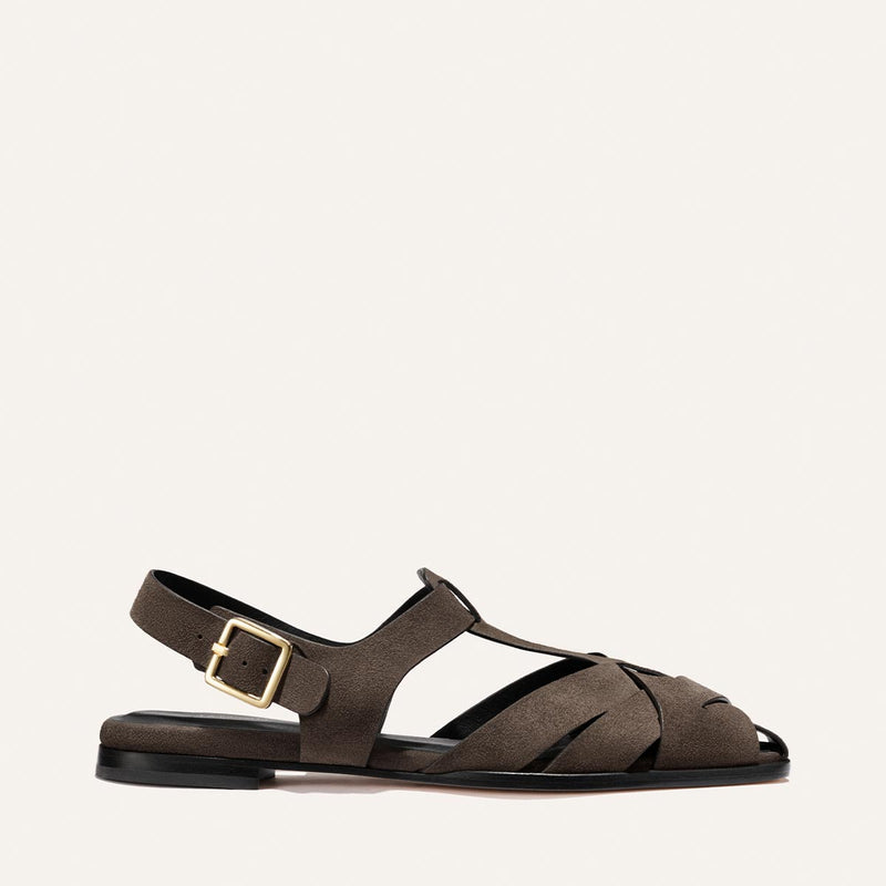 The Calypso Fisherman by Margaux in English Brown Suede is a flat sandal with closed toe, interwoven design, cutouts, ankle strap, and gold buckle for secure fit. Shown against a plain light background.