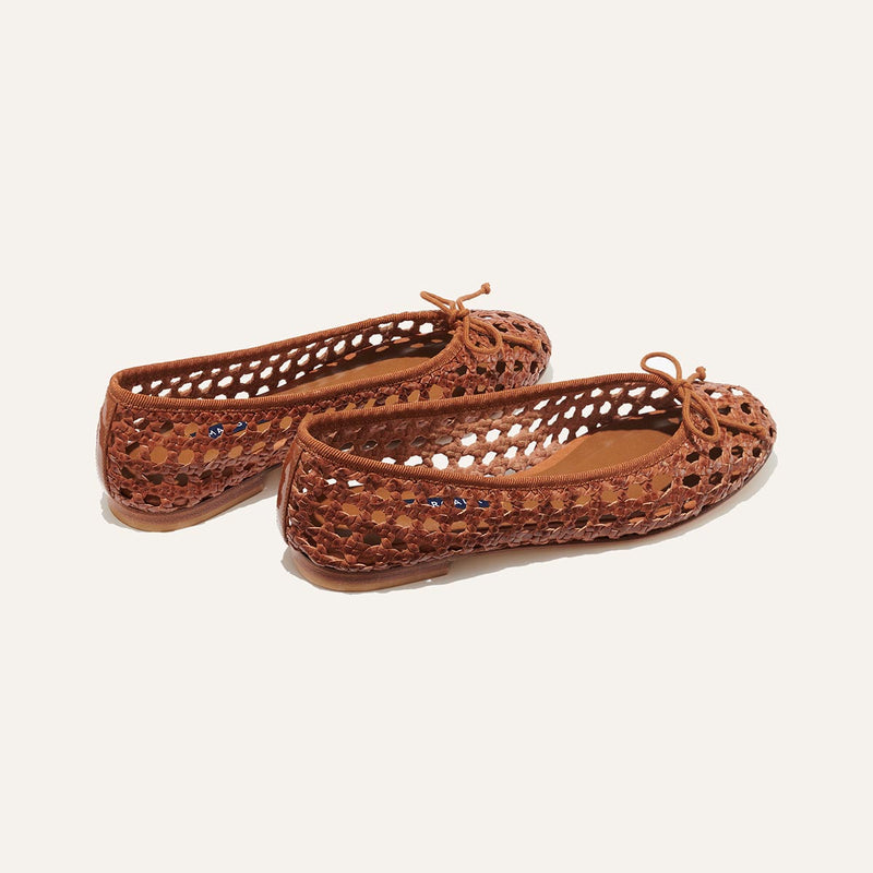 The Demi - Saddle Woven Leather by margaux-development are handmade in Spain, featuring brown woven leather, rounded toes, an open lattice design, and small front bows, shown on a plain light background.