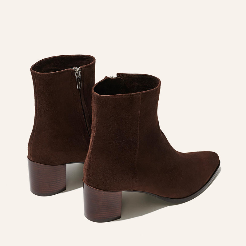 Margaux’s The Downtown Boot First Edition in Chocolate Suede features a western-inspired, minimalist design with medium block heels and side zippers, shown on a light background.