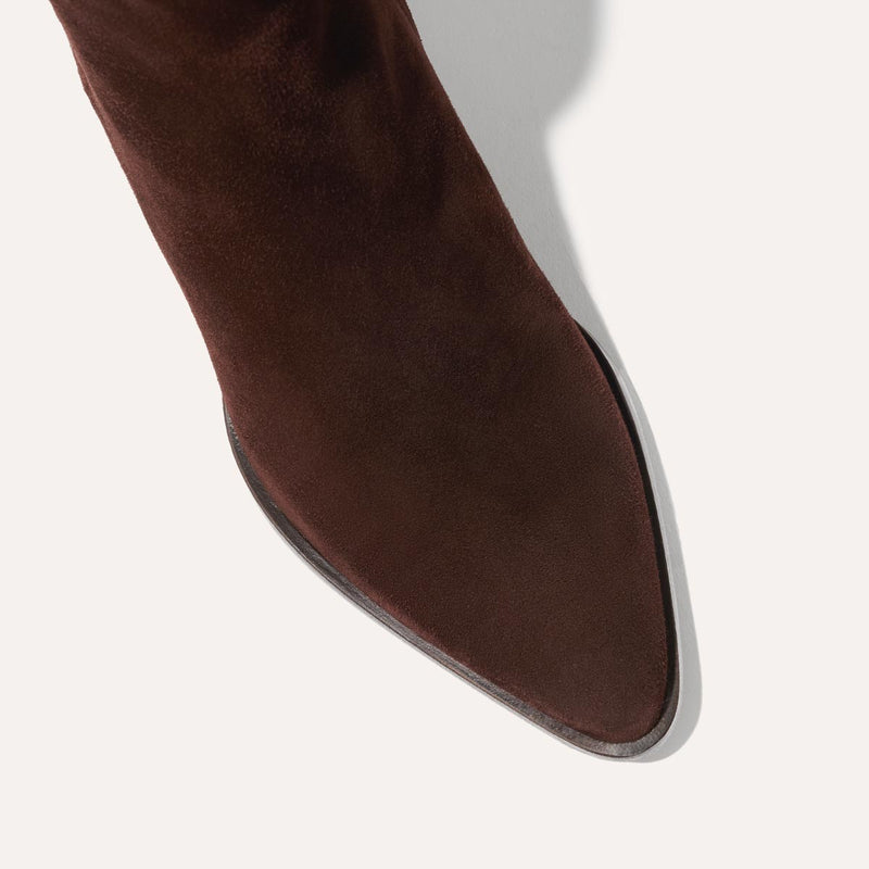 Close-up of the pointed toe on Margaux's The Downtown Boot First Edition in Chocolate Suede, a western-inspired ankle boot shown from above against a light background.