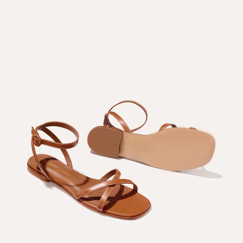 The Flat Sandal in saddle brown nappa, a minimal sandal featuring thin, flattering straps with a subtly square toe.