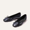 The Fonteyn - Fumo Python Embossed by Margaux: black ballet flats with shiny blue python embossing and black bows on the toes, shown on a light background.