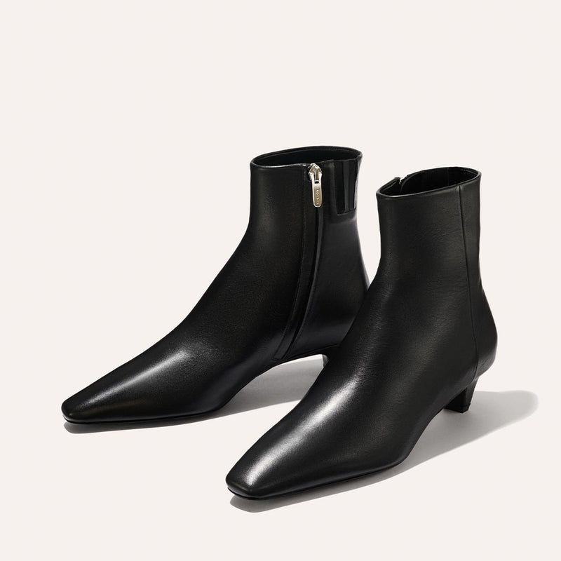 The Inga - Black Calf by margaux-development: sleek black ankle boots with low heels, side zippers, and pointed toes—an NYC-inspired essential shown on a light background.