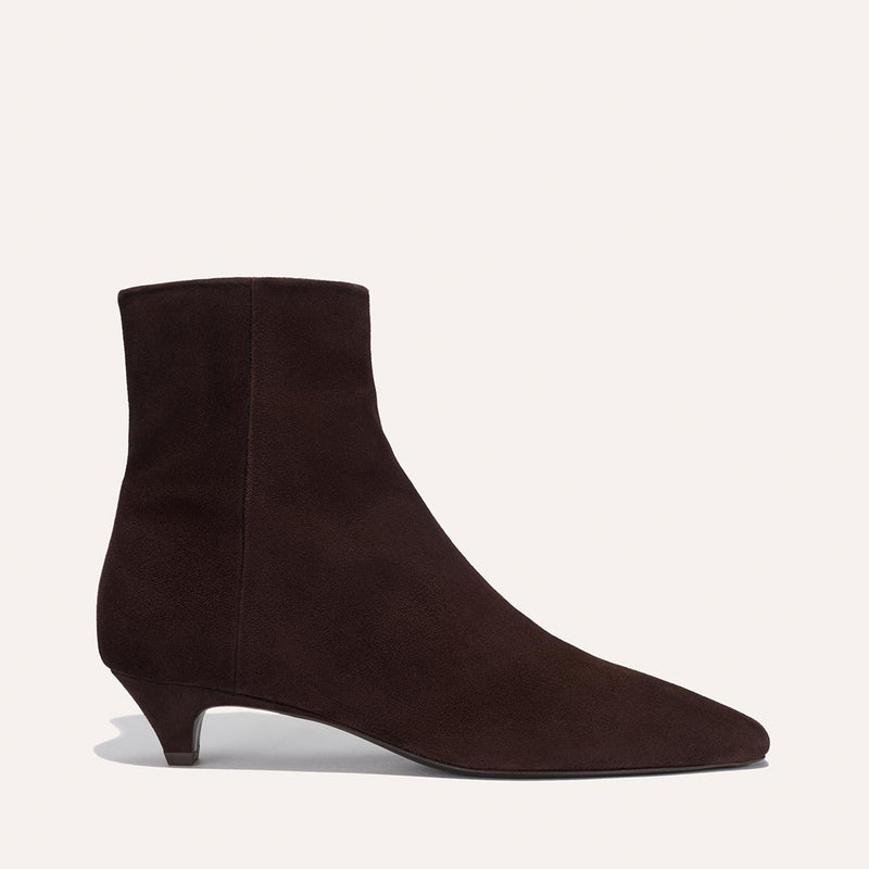 The Inga - Espresso Suede by margaux-development is a dark brown suede ankle boot with a pointed toe and low heel, ideal for city life, shown in profile against a plain light background.
