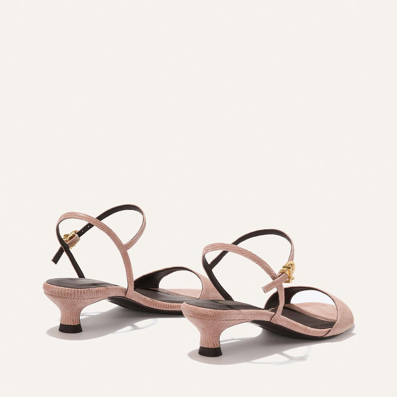 Pair of pink high-heeled sandals with thin straps on a light beige background