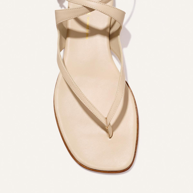 A close-up of Margaux’s The Palermo Sandal - Magnolia Nappa, showcasing its square toe, thin crisscross straps, and cushioned insole—ideal summer footwear—displayed against a white background.