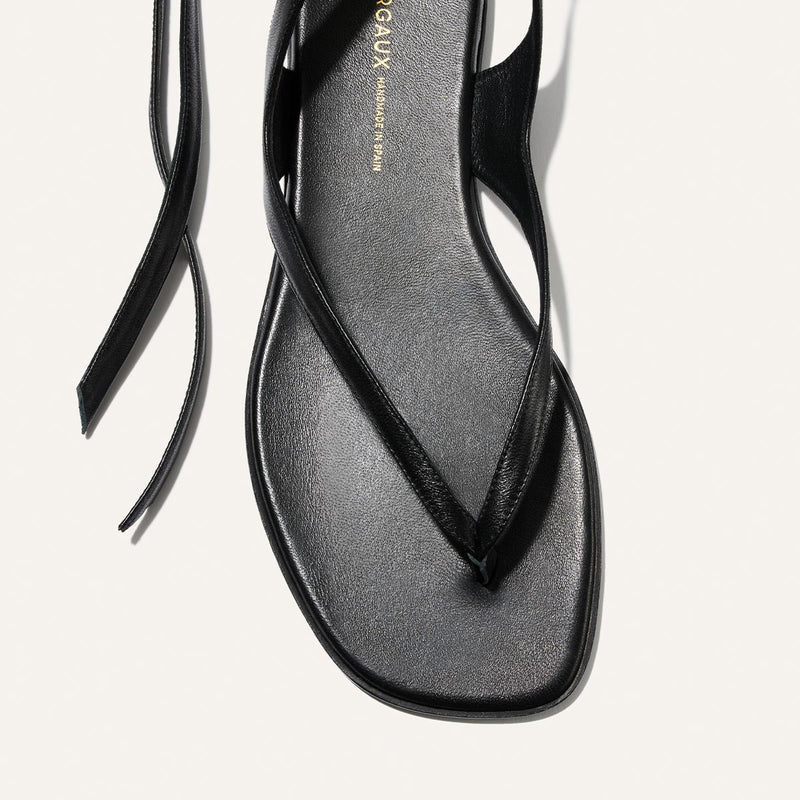 Black sandal with a minimalist design on a light gray background