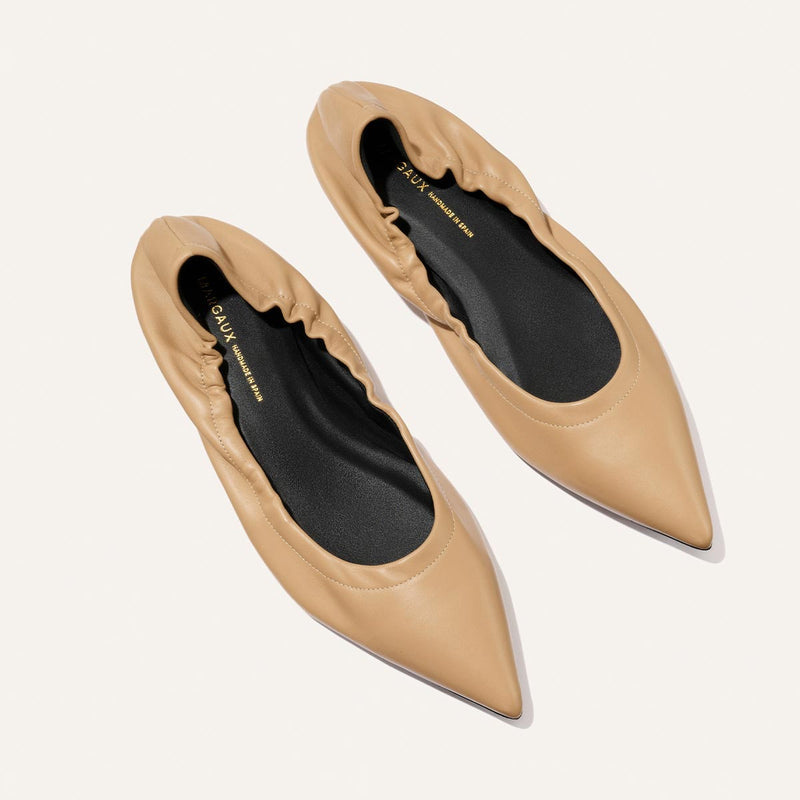 The Roma - Praline Nappa by Margaux: tan pointed-toe flats with gathered, elasticized edges and black insoles, shown on a light background.