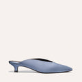 The Romy by Margaux in Slate Blue Satin is a chic mule featuring a pointed toe and low heel, shown on an off-white background—an elegant and comfortable choice for parties.